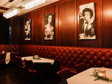 Tufted red leather banquette seating at Giancarlo's Sicilian Steakhouse — Italian fine dining room with dark wood paneling and classic booth upholstery
